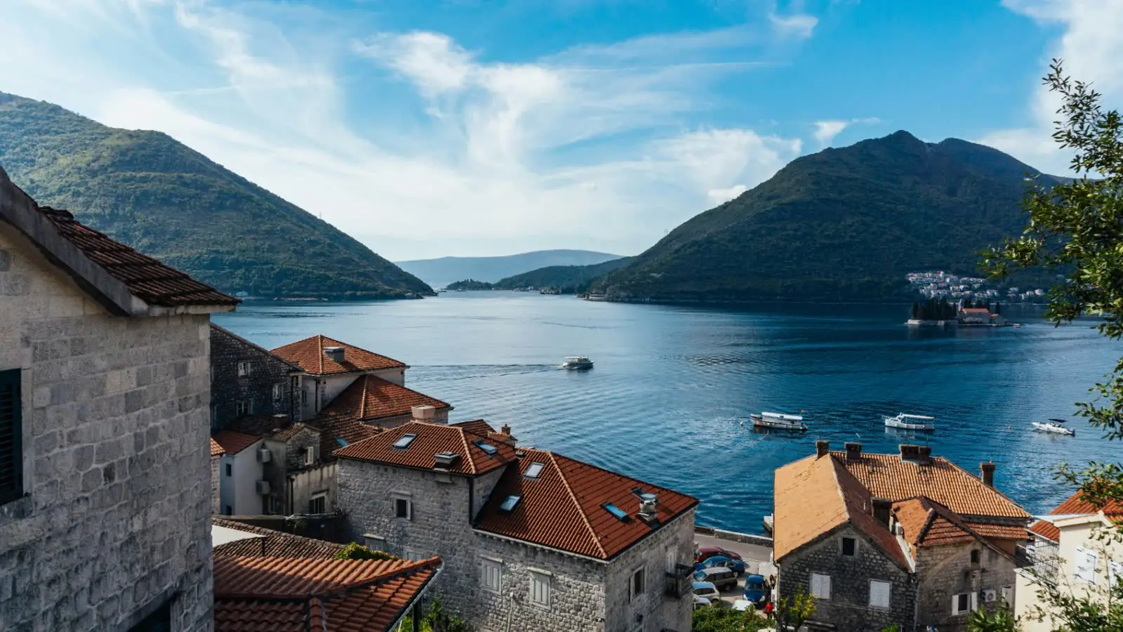 Terracotta rooftops of Perast and the Bay of Kotor at golden hour, viewed from the coastal road