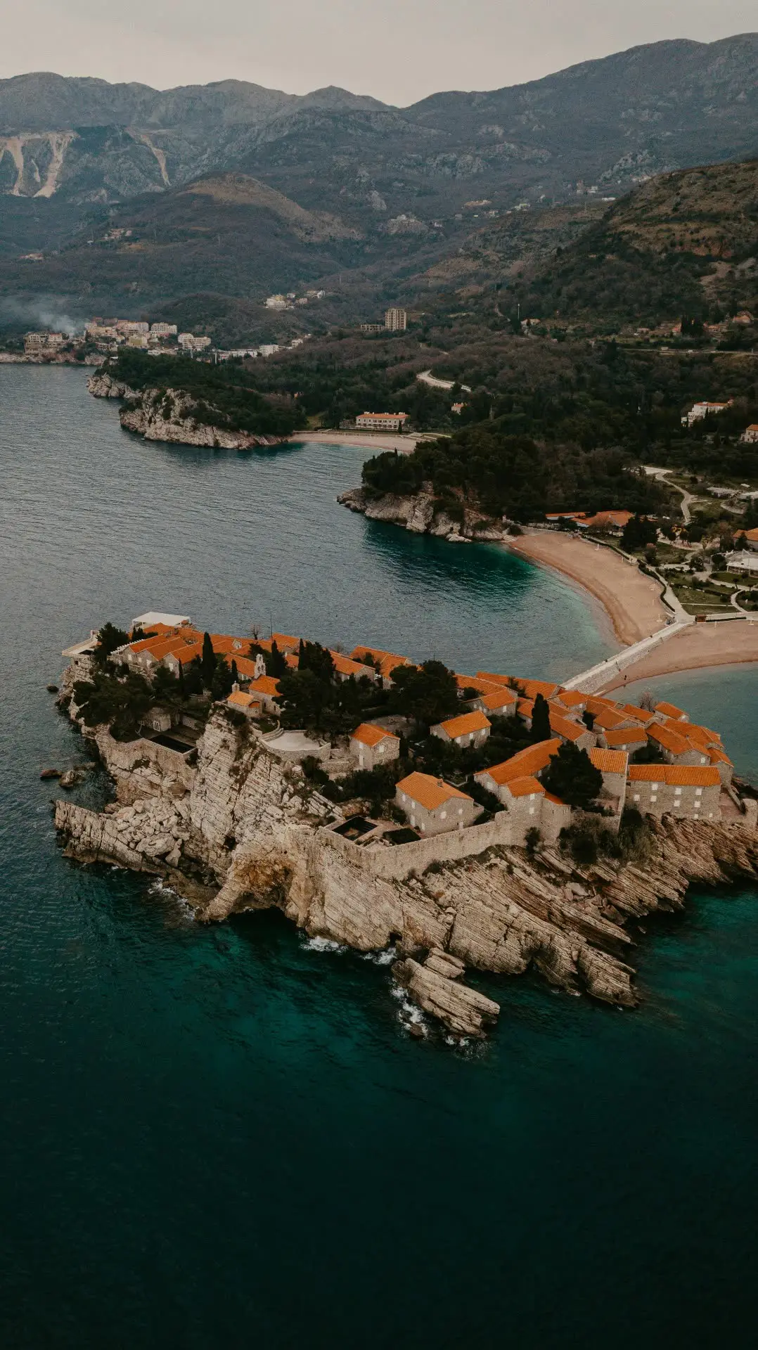 Pink-tiled rooftops of Sveti Stefan island seen from the coastal viewpoint above the village